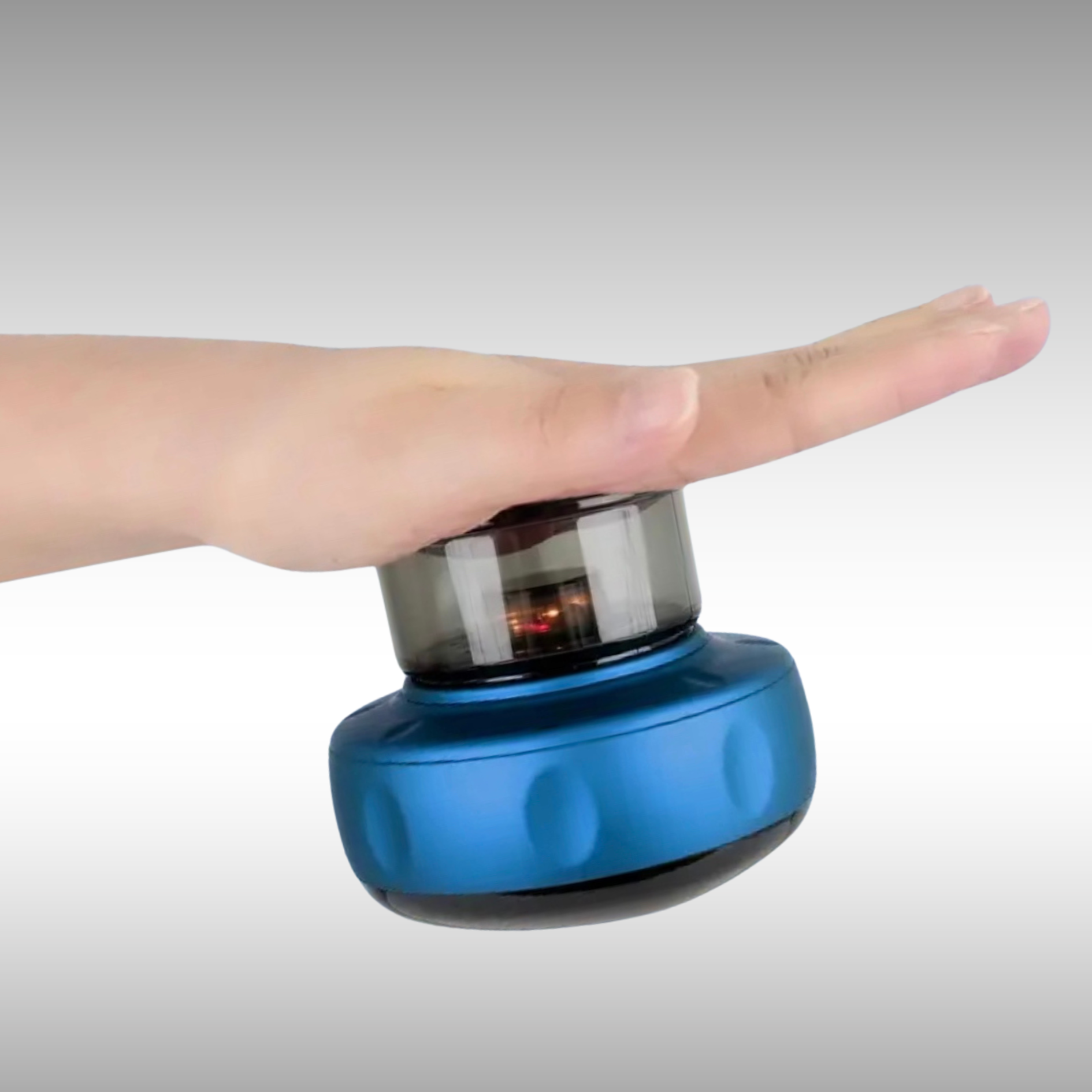 Image of NuLYFF™ Intelligent Cupper showing off its powerful patented dynamic suction technology as it hangs upside down suctioned to a palm of a hand. this cupping therapy device has redlight shining onto the hand.